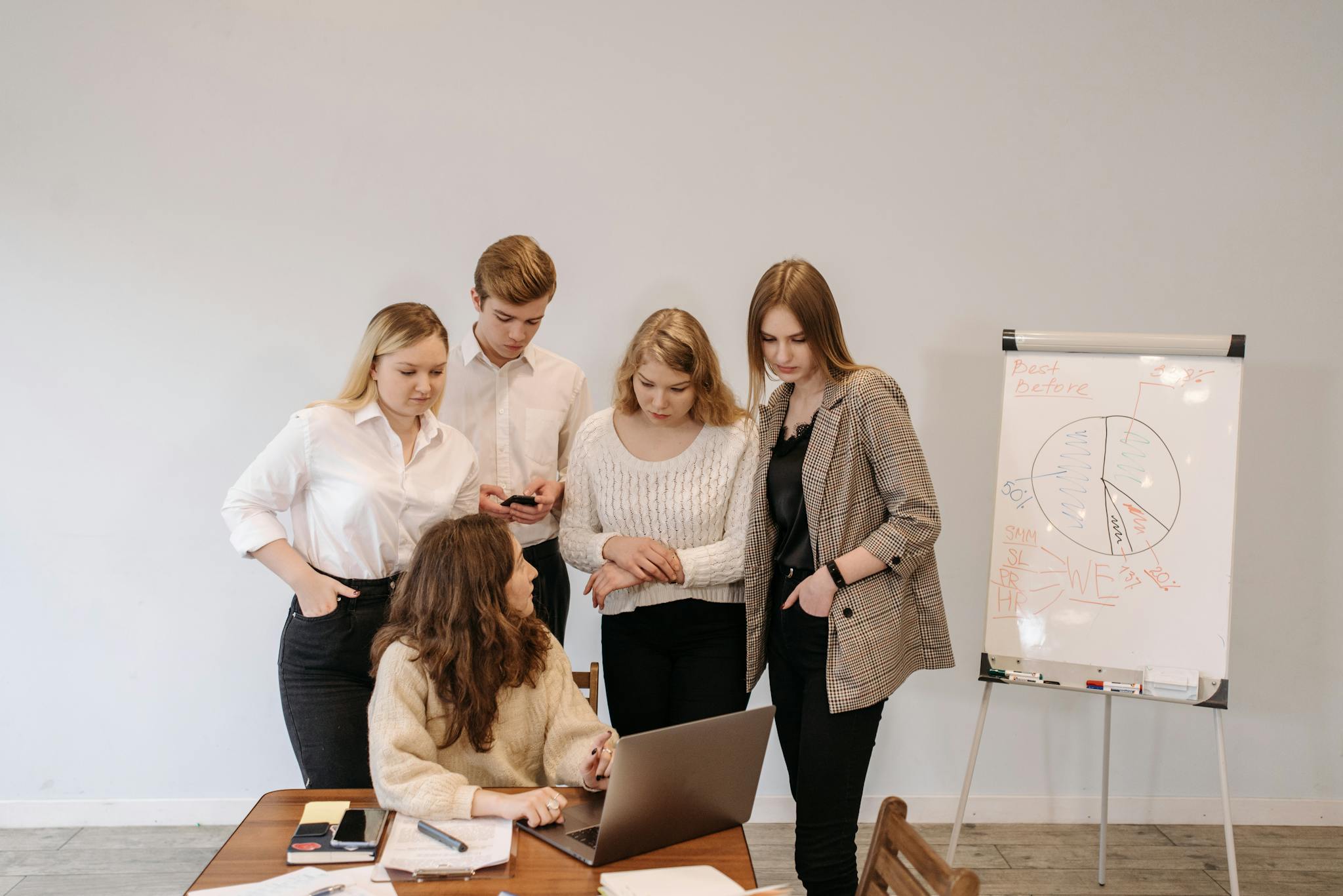 A group discussing a project around a laptop in a modern office setting.