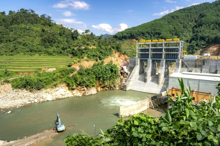 Scenic view of a hydroelectric dam nestled in a lush green valley, surrounded by hills.